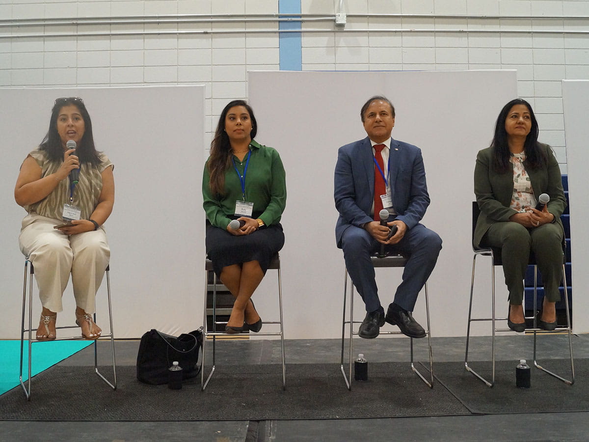 Four people sitting side-by-side on a stage.
