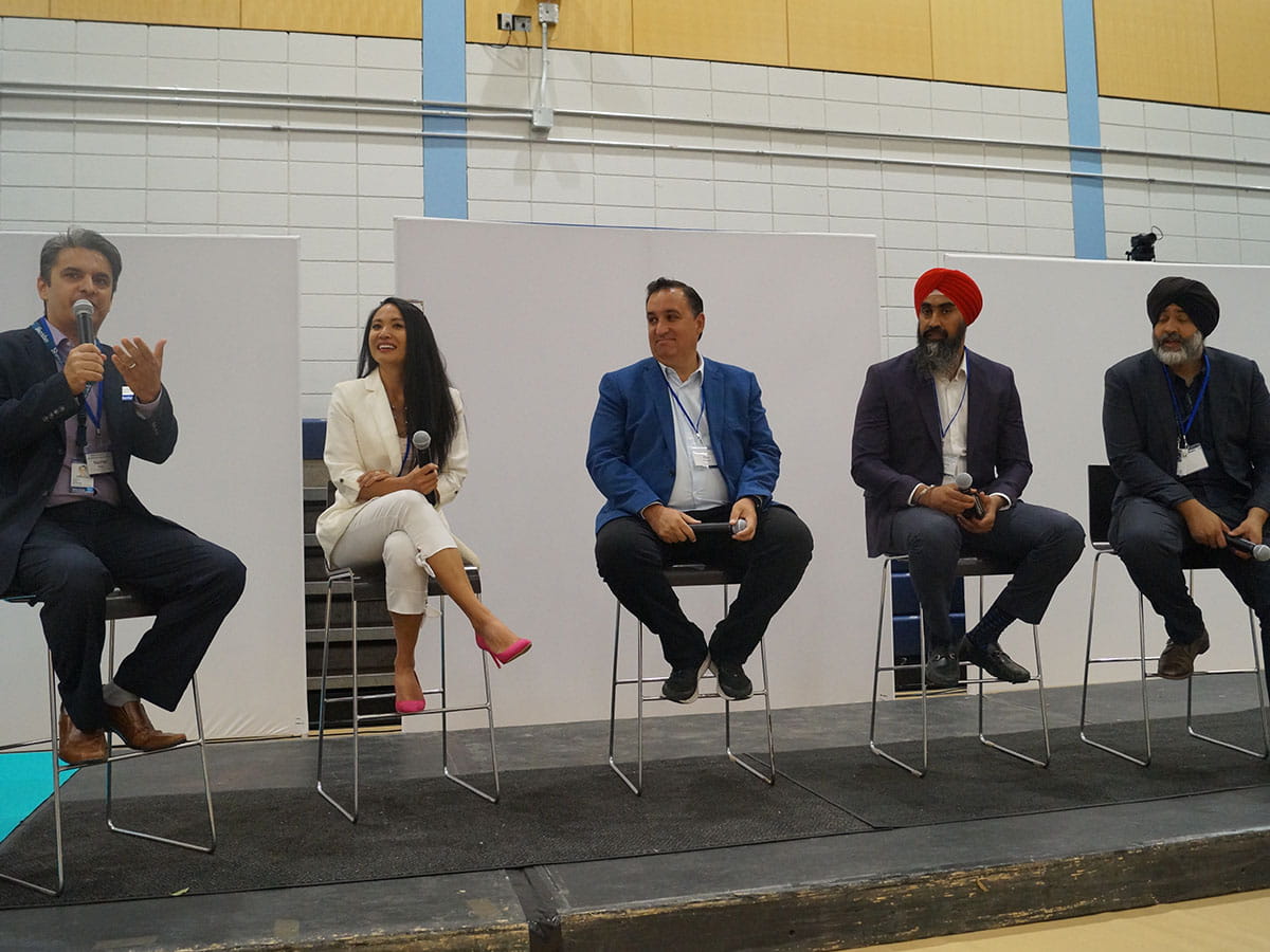 Five people sitting side-by-side on a stage.