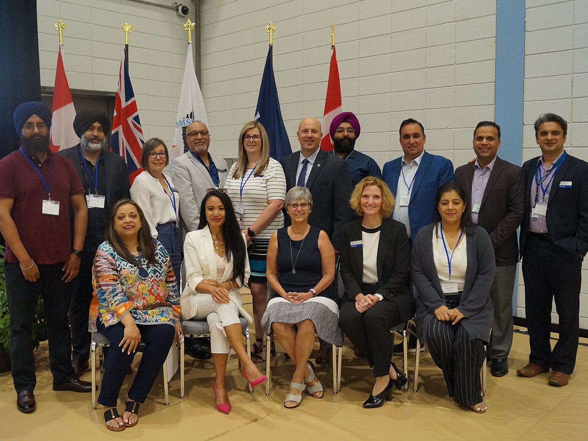 A large group posing for a photo. Ten people standing behind a row of five people seated in front of them.