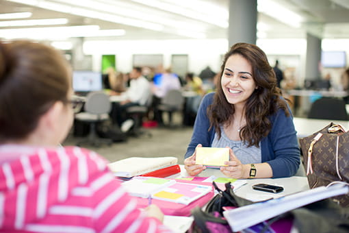 Two students in conversation while sitting on opposite sides of a table