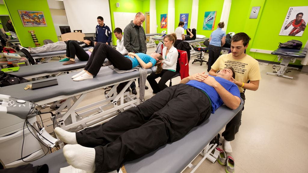 Athletic therapy room filled with therapy tables and students practicing on one another