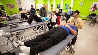 Athletic therapy room filled with therapy tables and students practicing on one another