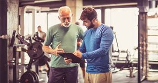 Two people talking in a gym while one holds a clipboard