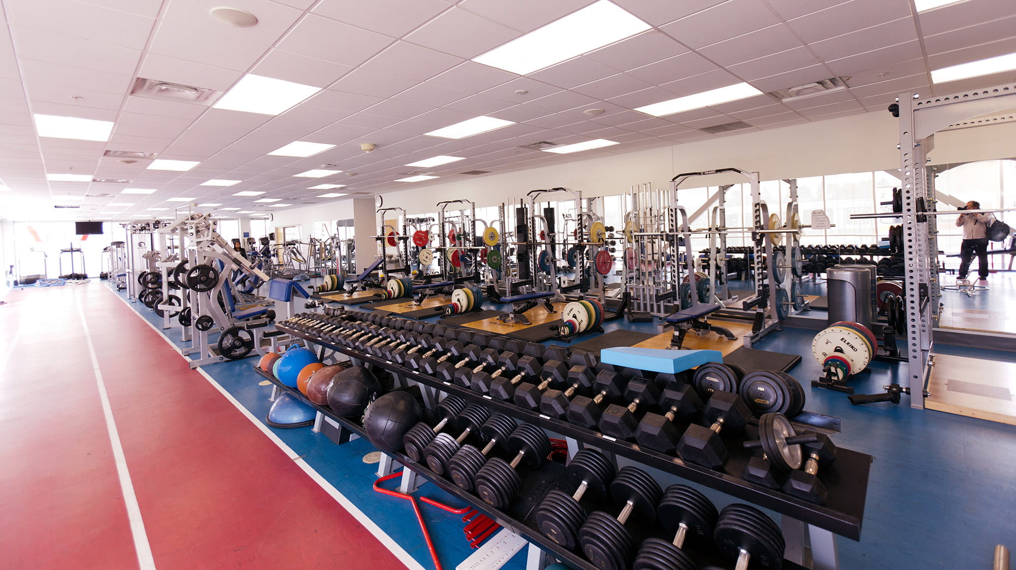 A long row of exercise machines and weights at the Bruins Athletic Complex