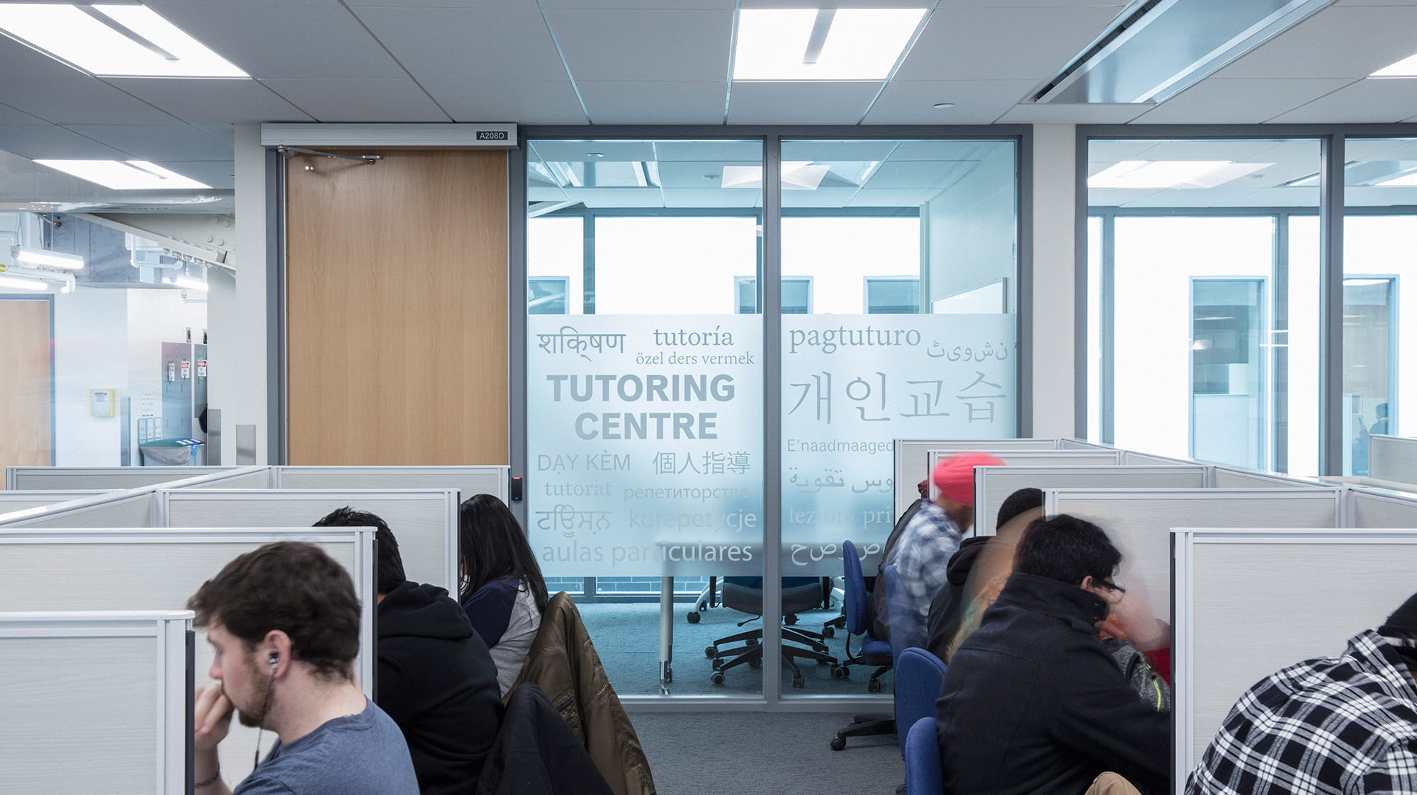 Students working at computer stations near a glass door that says "Tutoring Centre"