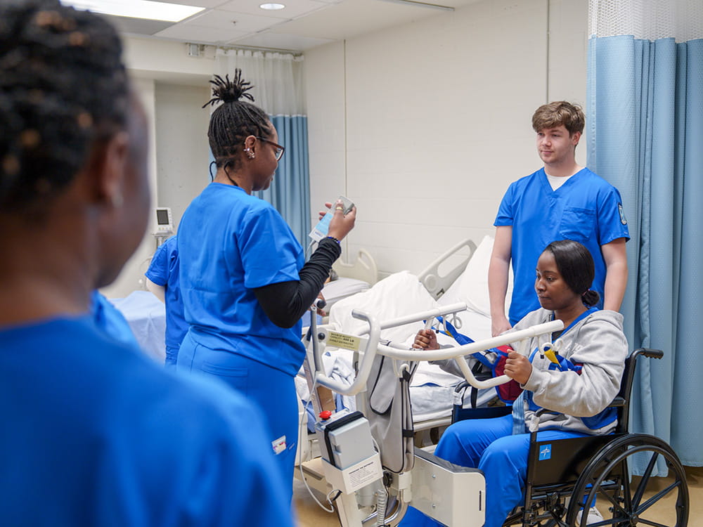 Students participating in a real-world care classroom setting with a wheelchair.
