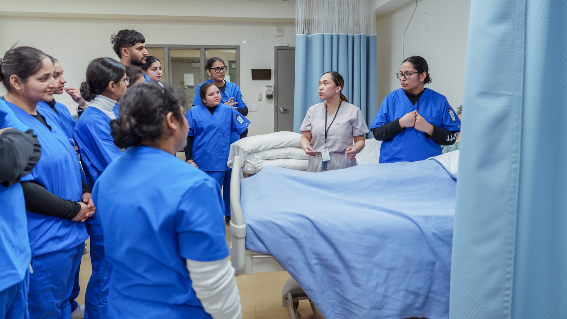 Group of students surrounding a hospital bed.