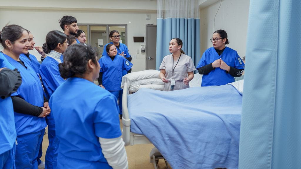 Group of students surrounding a hospital bed.