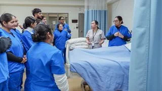 Group of students surrounding a hospital bed.