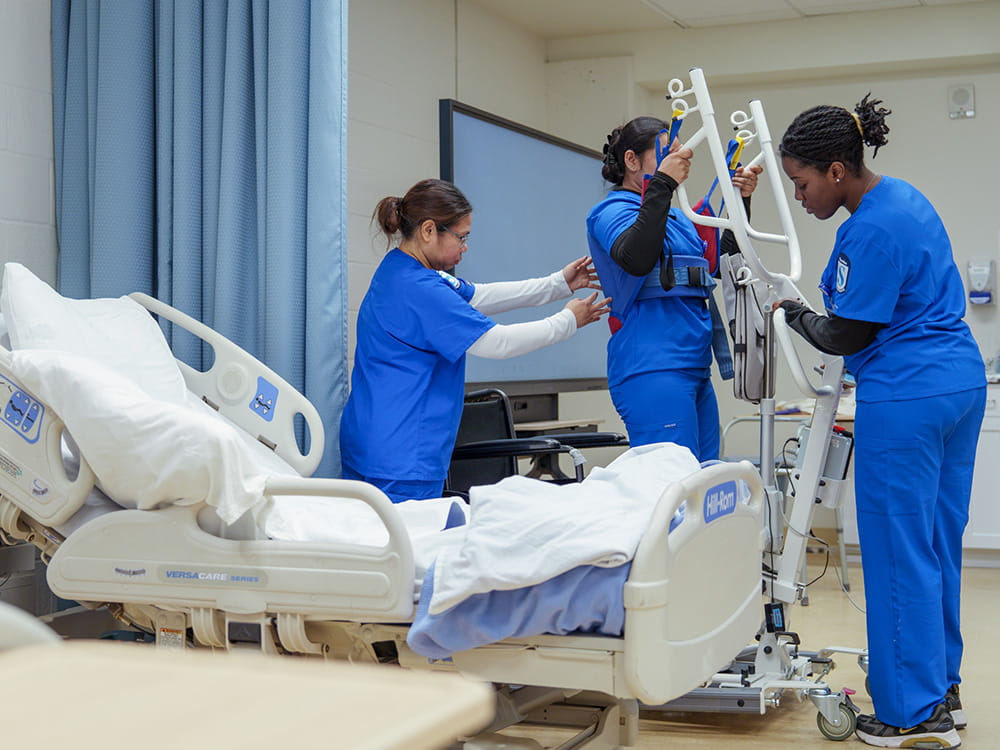 Two students assisting another who is using a physical assistive device.