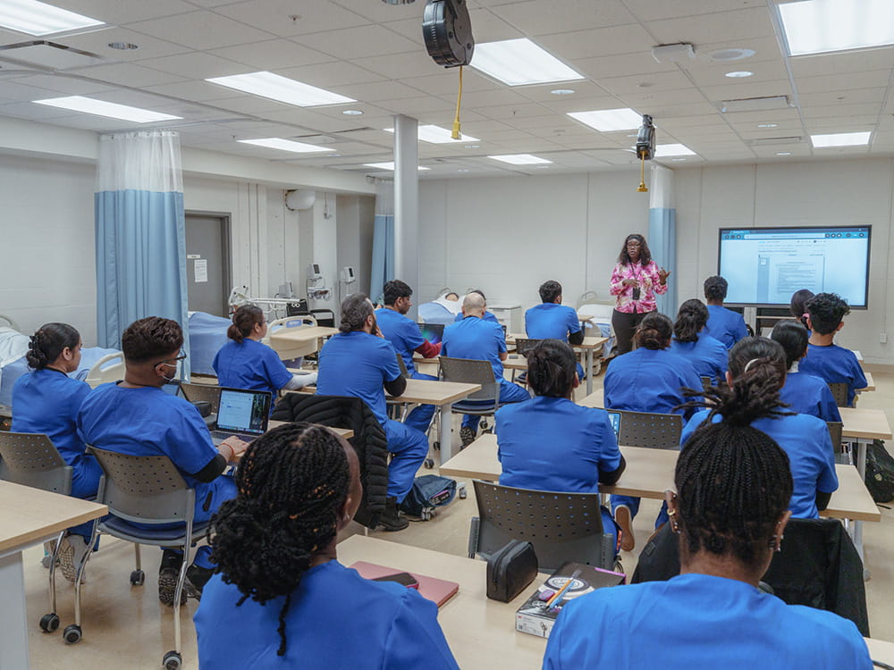 Students seated in a classroom while an instructor stands up front.