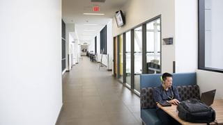 A student working on a laptop at a booth in the hallway
