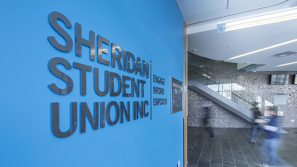 A large blue Sheridan Student Union sign in a hallway