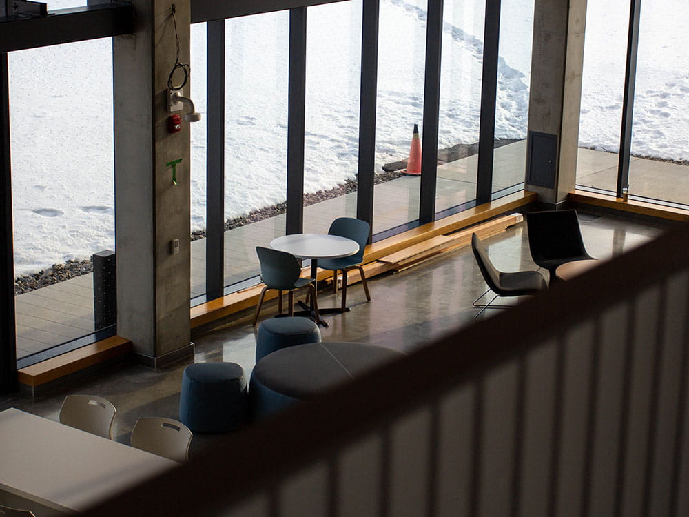 Looking down at the cafeteria seating area surrounded by glass windows in the Student Centre at Hazel McCallion Campus.