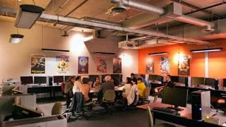 An instructor talking to a group of students in a room with lots of computers and posters of animated films on the walls