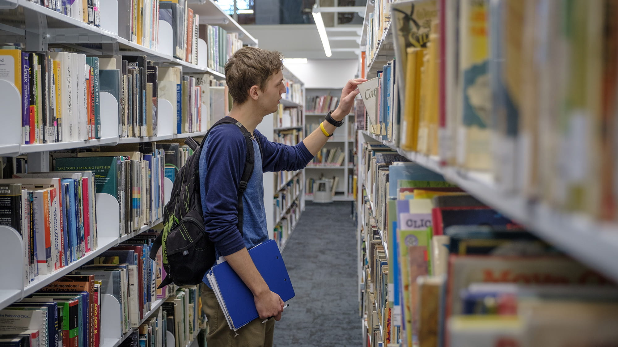 A student selecting a book off the shelf in the library