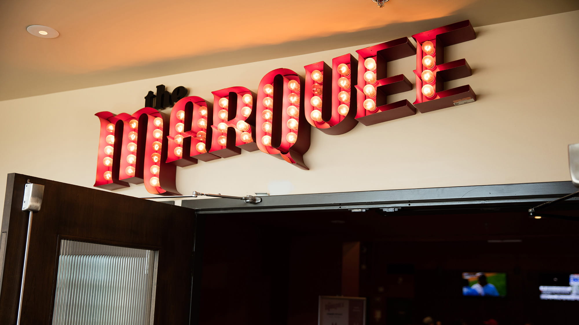 The Marquee sign with red letters and lights over the door to the pub