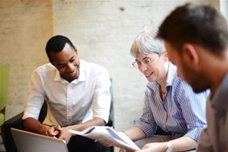 Multiple seated people looking at a document