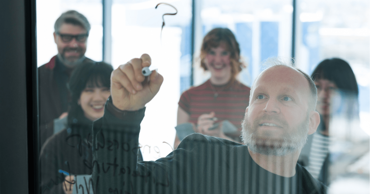 Five people writing on a board