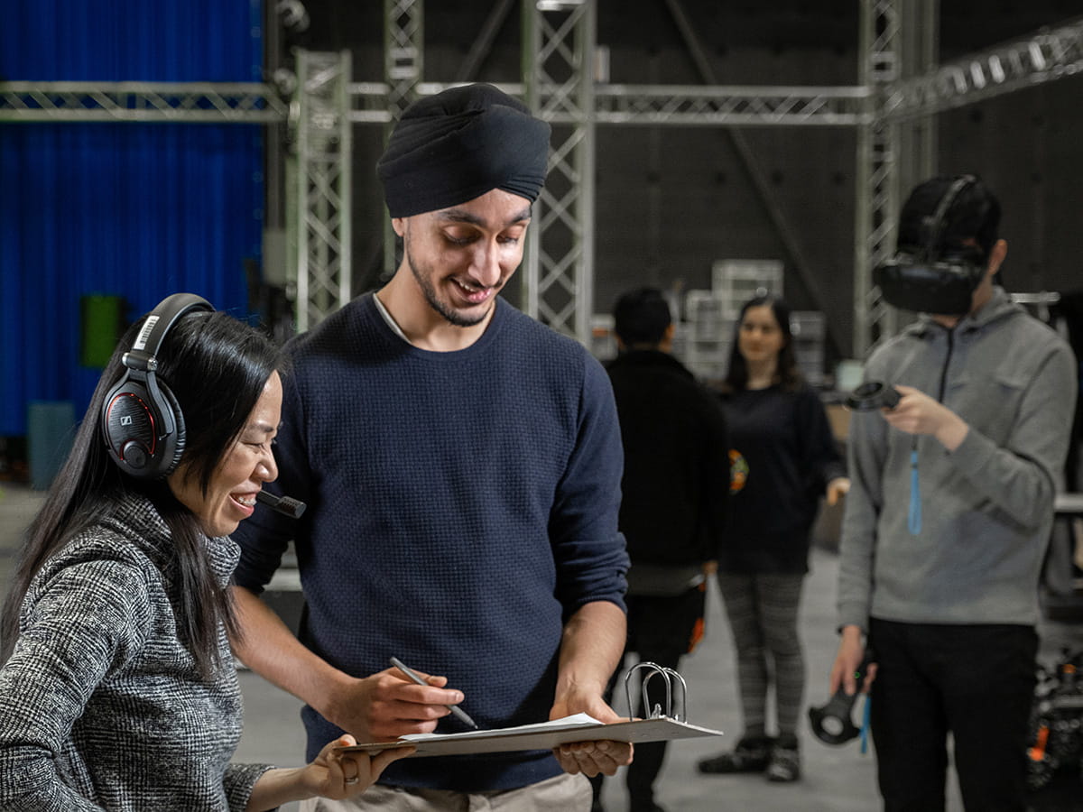Two people smiling while looking down at a clipboard