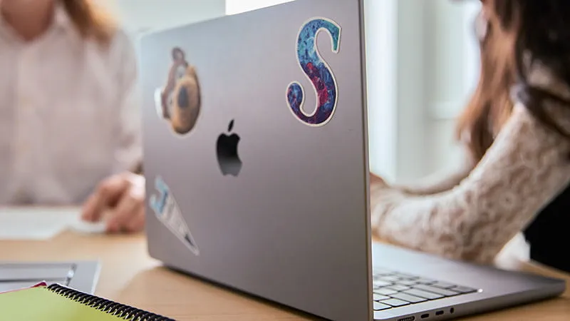 Close-up of laptop lid with a Sheridan 'S' and Bruno stickers on it