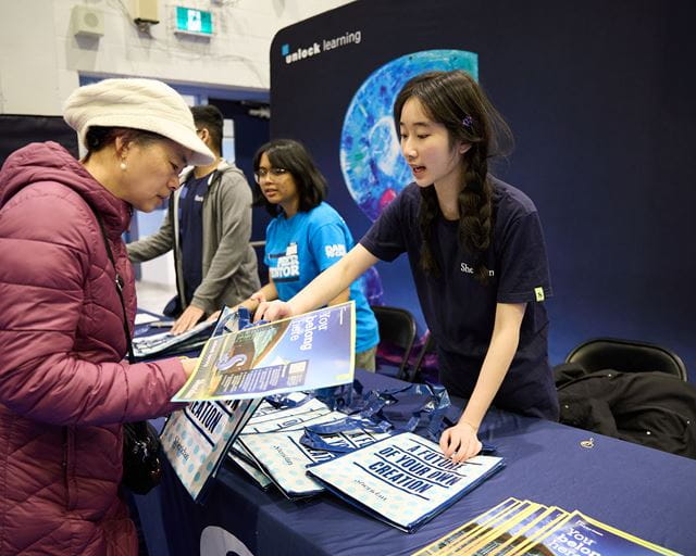 A Sheridan representative sharing a brochure with a visitor across a table during an event