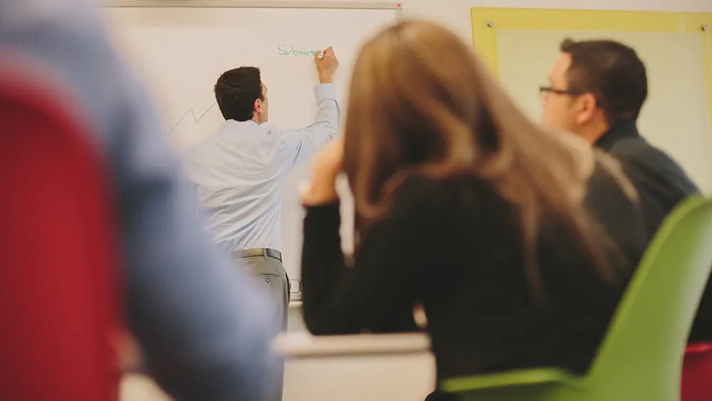 Group watching someone write on a whiteboard.