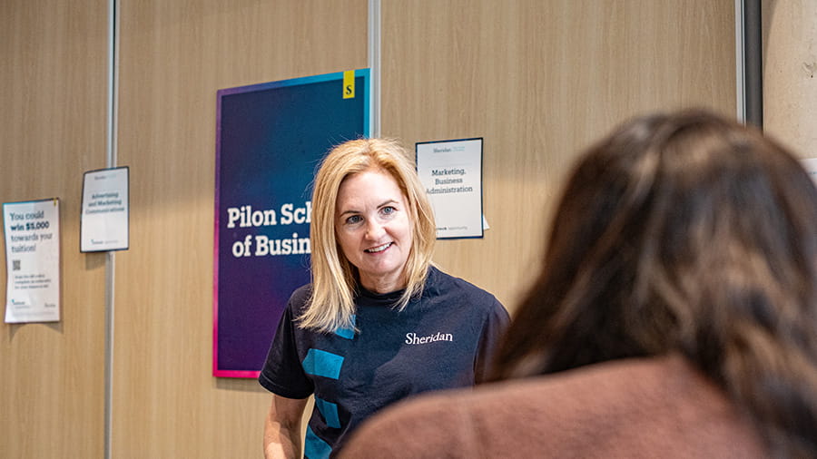 Representative from Pilon School of Business talking to an Open House attendee