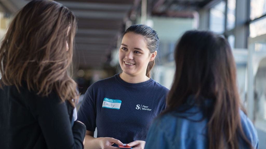 Peer mentor speaking to students on campus