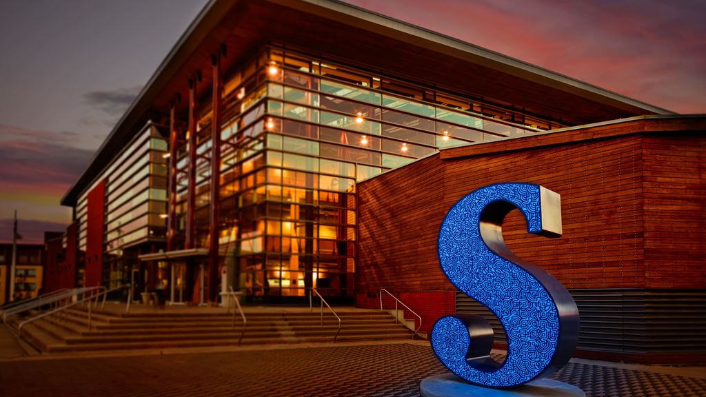 An external view of a building with the Sheridan "S" sculpture in front of it.