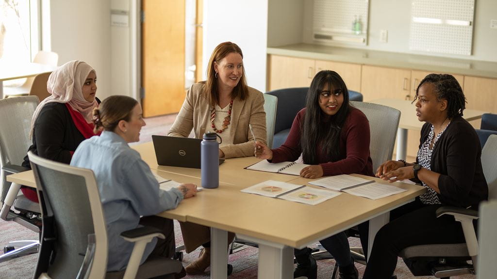 A group of people seated around a table having a discussion.