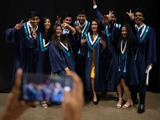 A group of graduates smiling and posing in graduation attire