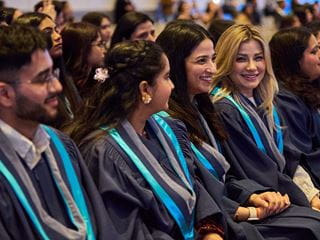 A group of graduates sitting in chairs in graduation attire