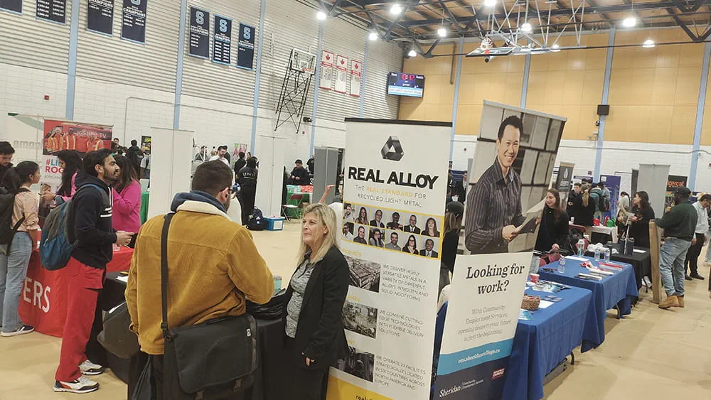 Two people talking while standing next to a large vertical banner