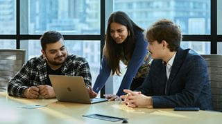 Three students looking at a laptop screen