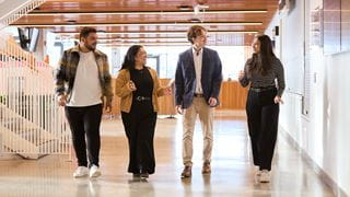 Four students walking down a hall and talking