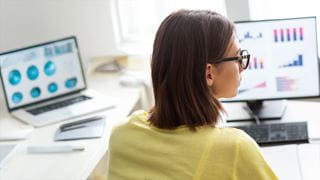 A person looking at data graphs on a computer monitor