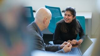 Student and instructor talking in front of a laptop
