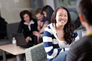 A student smiling as she sits with a peer.