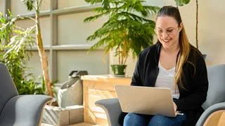 Person seated in a chair, working on a laptop