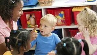 An adult sitting on the floor with a group of children in a childcare setting