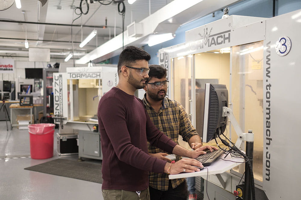 Two students standing at a terminal in Sheridan's Centre for Intelligent Manufacturing