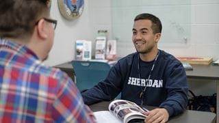 Student talking to another across a table