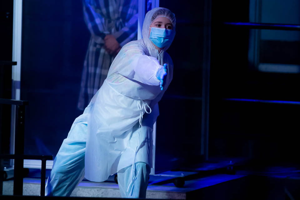 Actor performing dressed in a mask and personal protective equipment