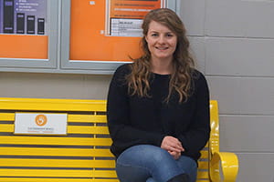 Photo of Journalism alumna Christy Janssens sitting on the Friendship Bench.