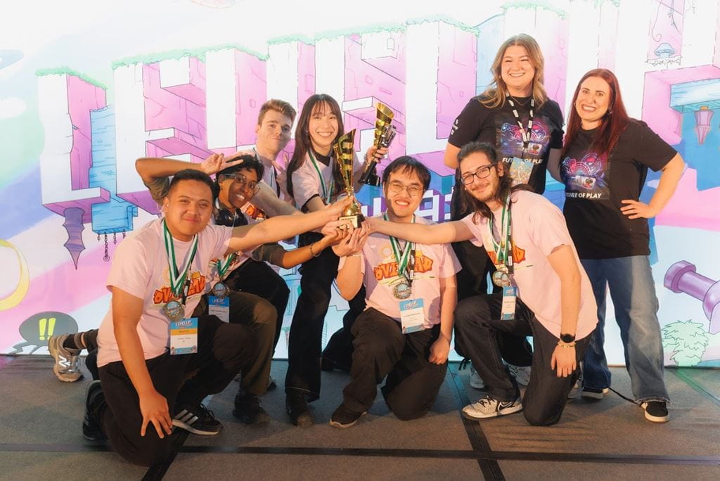 Members of the S-213 team wear pink shirts as they pose for a photo after winning the Best Overall Game award at the Level Up Showcase