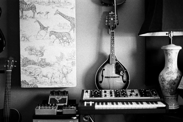 A sitar leaning up against the wall behind a keyboard