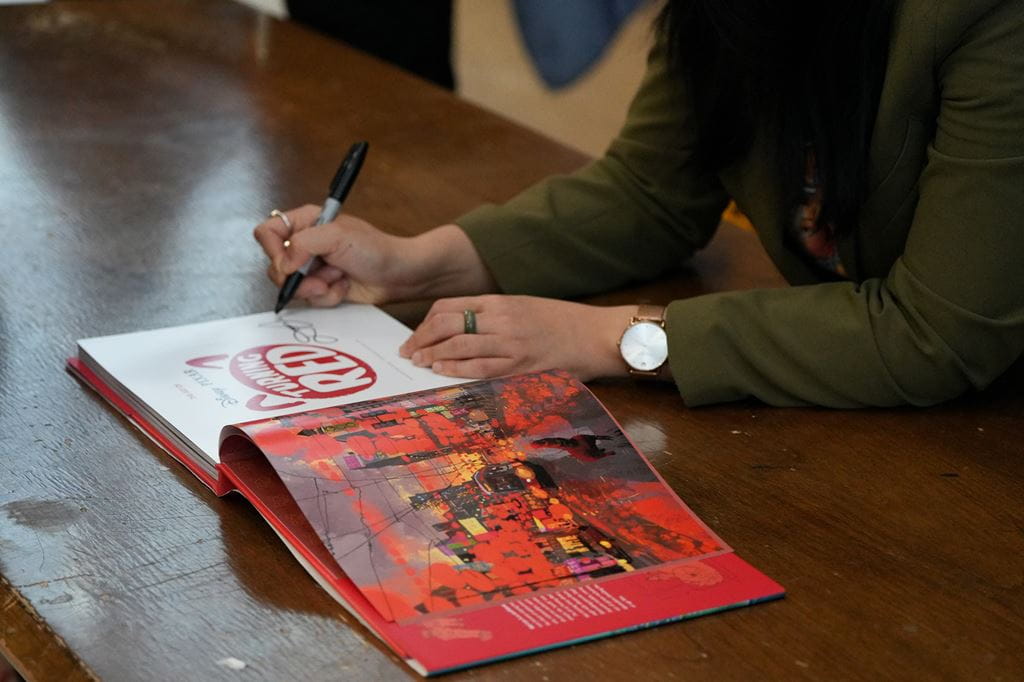 A close-up of Domee Shi signing a copy of The Art of Turning Red
