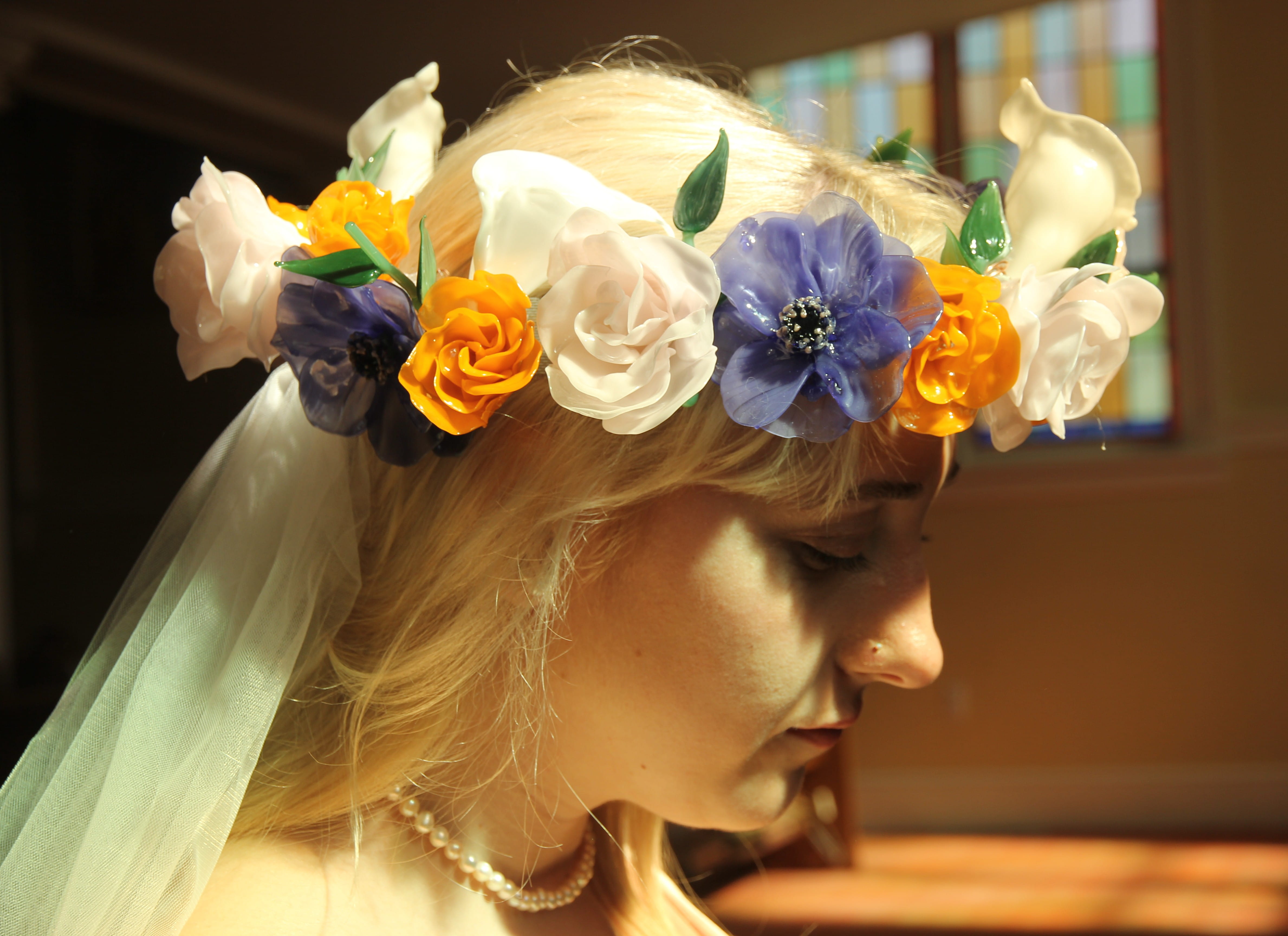 A woman wears a colourful crown of glass flowers on her head.
