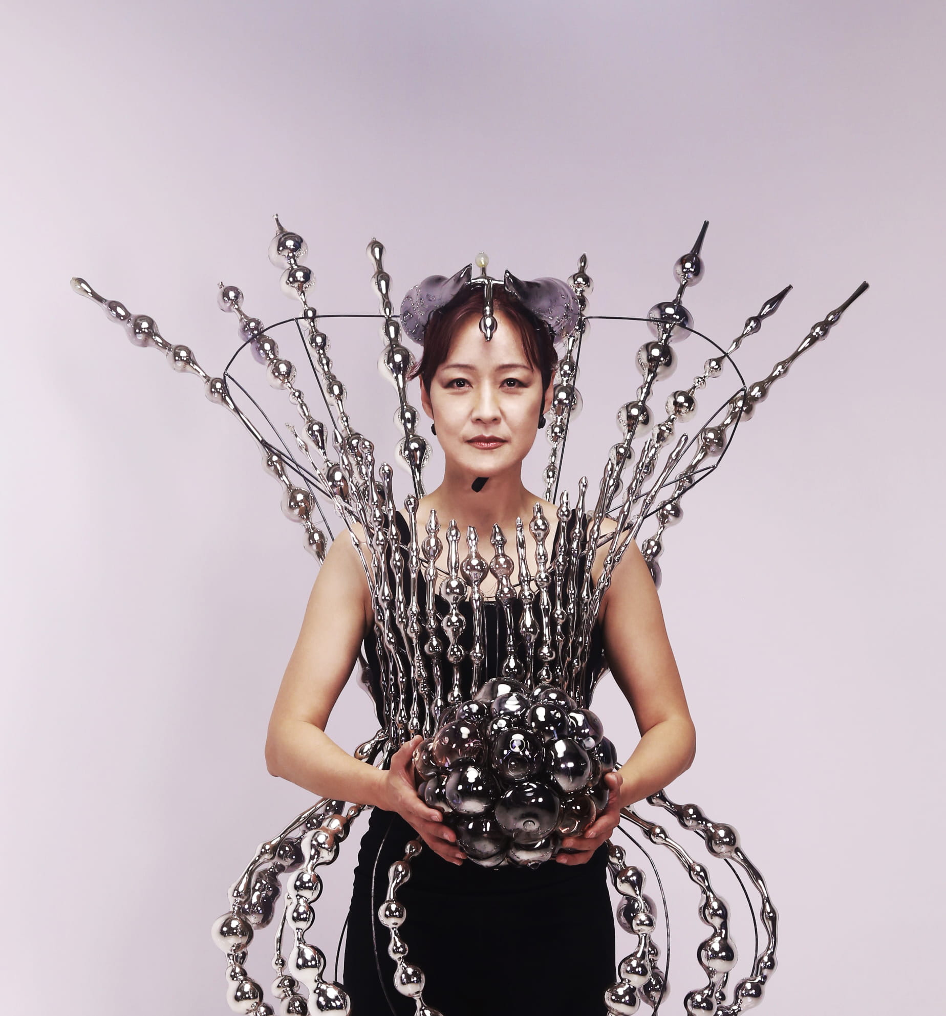 Instructor Jin Won Han wears an outfit made of glass while holding a glass ball.
